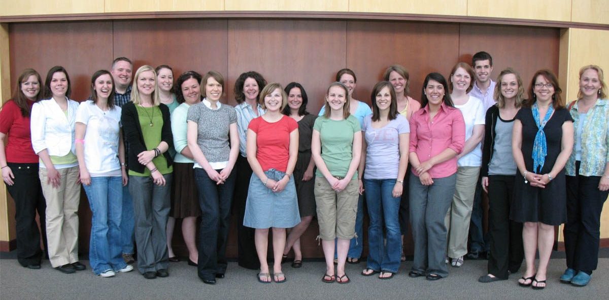 Cohort photo of 2008-2009 LEND trainees standing in front of wooden paneled walls.